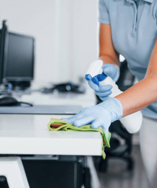 Close up view of woman in protective gloves that cleaning tables in the office